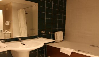 Un baño con lavamanos, espejo, bañera y cortina de ducha.