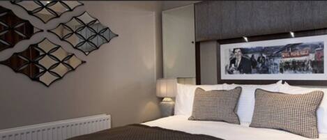 Une chambre d’hôtel avec un lit, une œuvre d’art accrochée au mur et un radiateur.