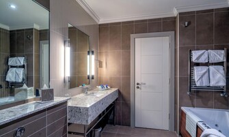 Un baño moderno con encimera de mármol, un espejo grande, toallero y bañera.