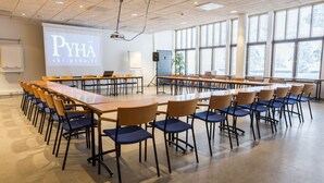 A conference room with a long table, chairs, a projector screen, and a whiteboard. - Hotel Pyhatunturi (Pyhätunturi)