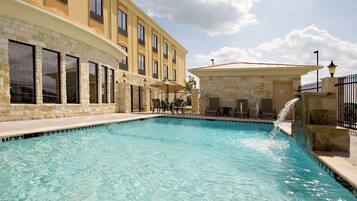 A swimming pool with a stone facade hotel in the background.