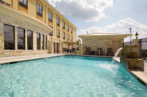 Una piscina con un hotel de fachada de piedra al fondo.