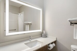 A modern bathroom with a large mirror, a sink, a toilet, and a towel rack. - Holiday Inn Express Suites Beeville by IHG (Beeville)