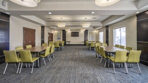 A conference room with a long table and yellow chairs, equipped with ceiling lights and a flat-screen TV. - Holiday Inn Express Suites Beeville by IHG (Beeville)