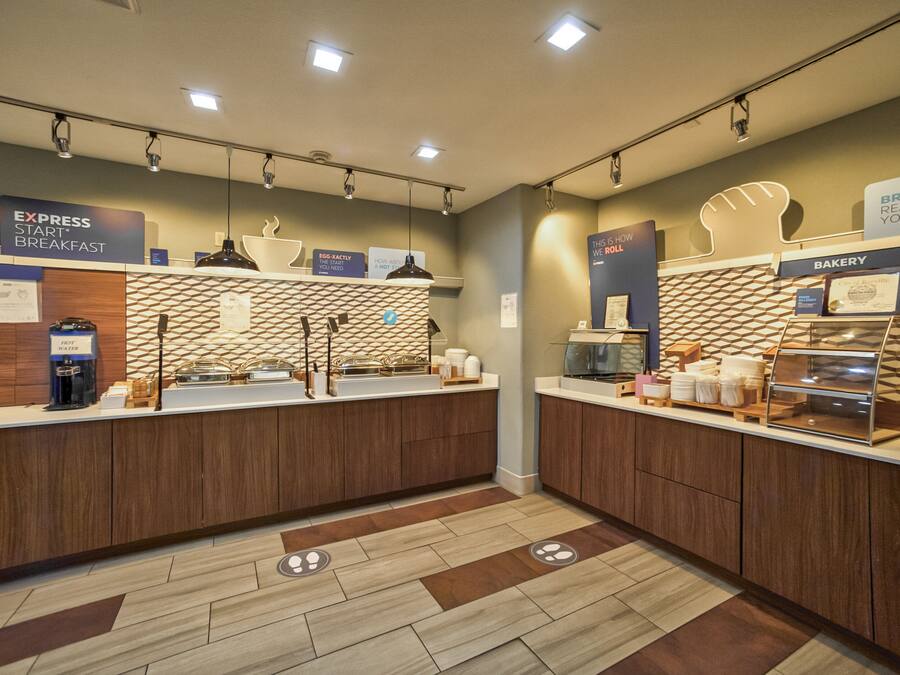 Un área de desayuno moderna con una barra de desayuno rápida, una sección de panadería y una exhibición de frutas.