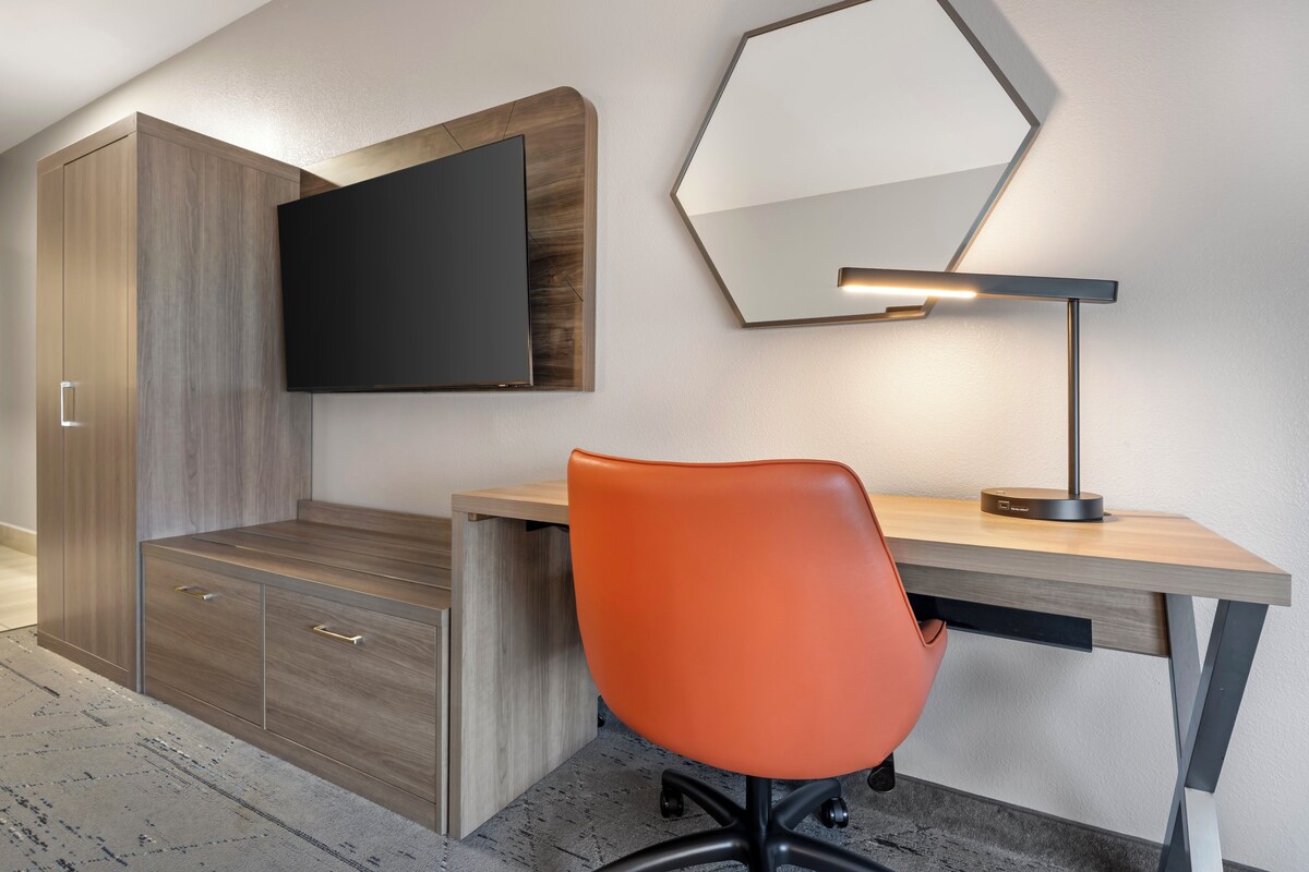 A modern office space with a desk, chair, and a mounted flat-screen TV.