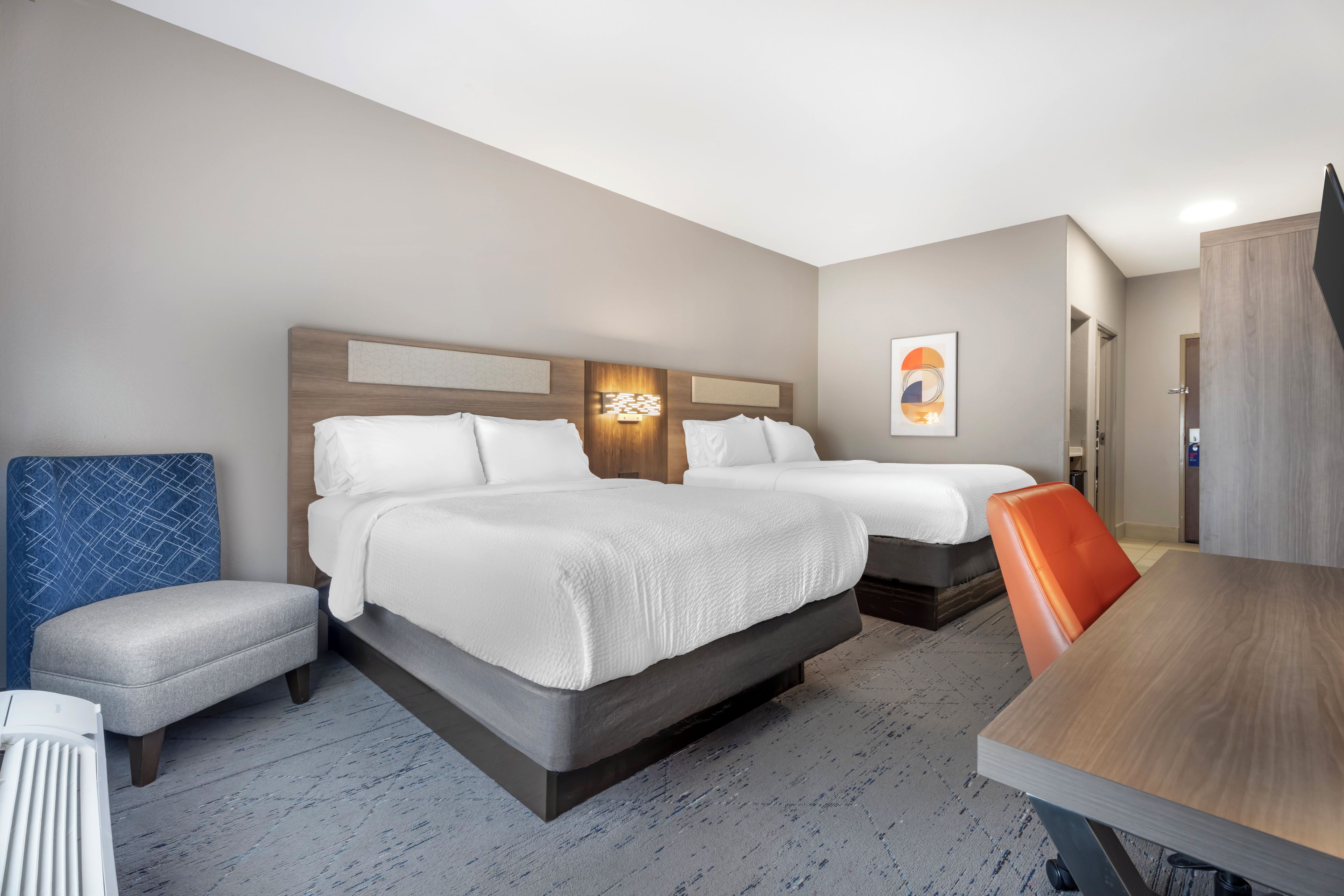Een hotelkamer met twee bedden, een bureau en een stoel.