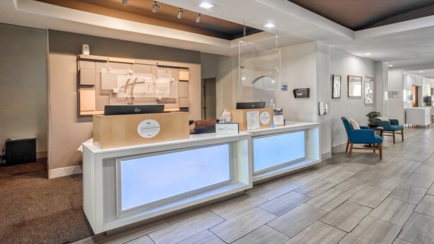 A hotel reception area with a modern design, featuring a reception desk, seating area, and a hallway leading to other rooms. - Holiday Inn Express Suites Beeville by IHG (Beeville)