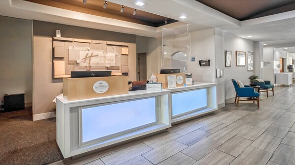 A hotel reception area with a modern design, featuring a reception desk, seating area, and a hallway leading to other rooms. - Holiday Inn Express Suites Beeville by IHG (Beeville)