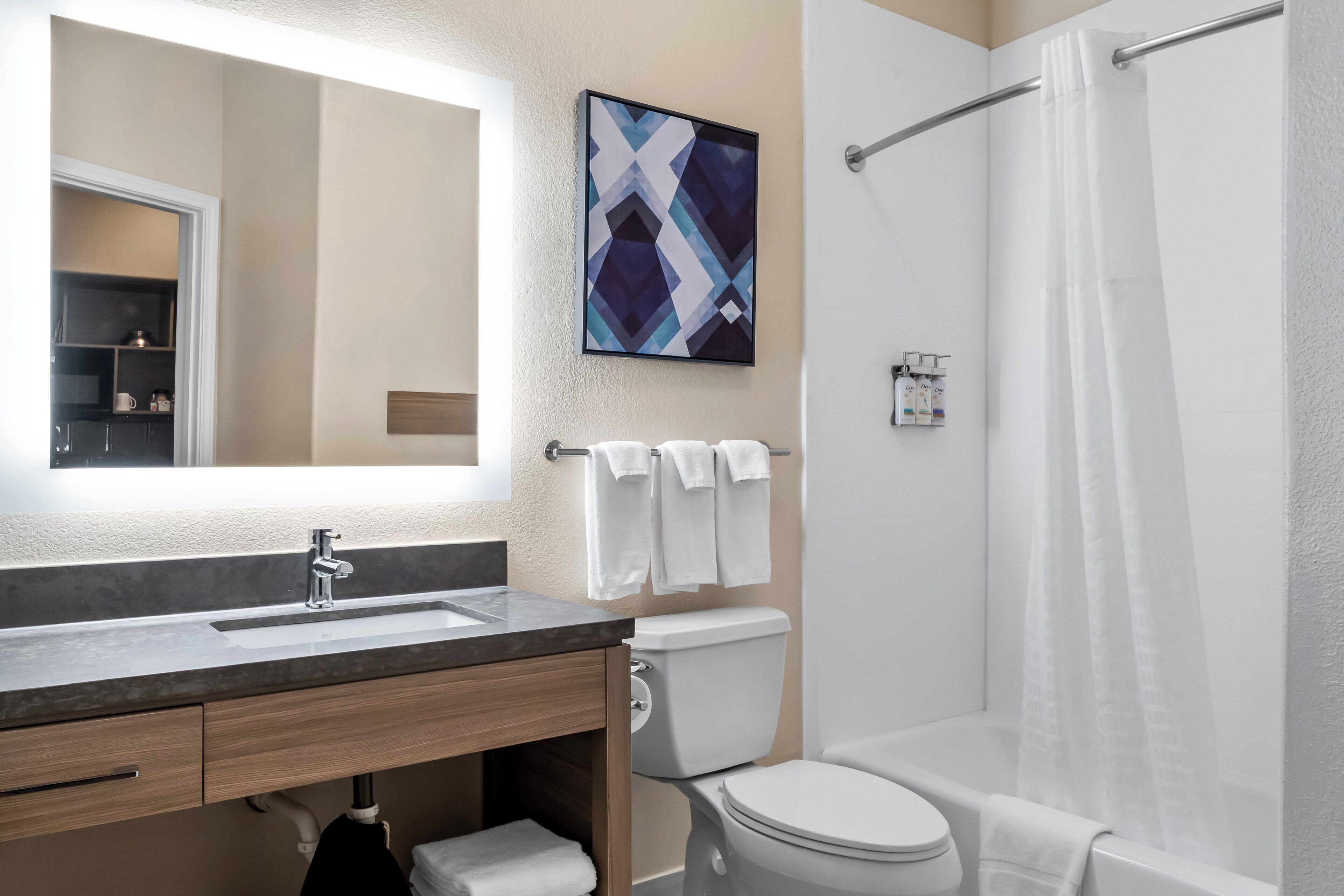 Un baño moderno con lavamanos, inodoro y ducha.