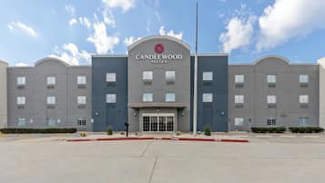 A multi-story hotel with a prominent entrance, a clear sky, and a parking lot in front.