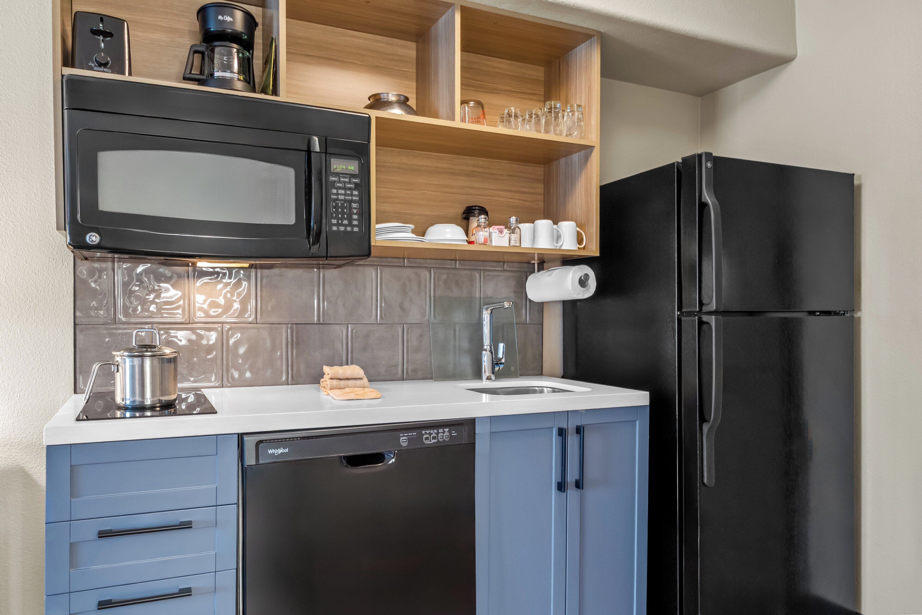 A modern kitchen with a black refrigerator, a built-in microwave, and a dishwasher.