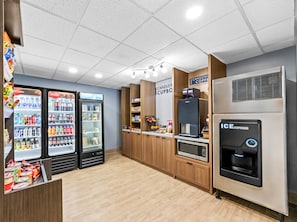 A modern coffee shop interior with vending machines, a coffee machine, and a microwave. - Candlewood Suites VICTORIA by IHG (Victoria)