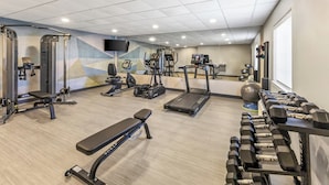 Un gimnasio con cintas de correr, bancos de pesas y mancuernas.