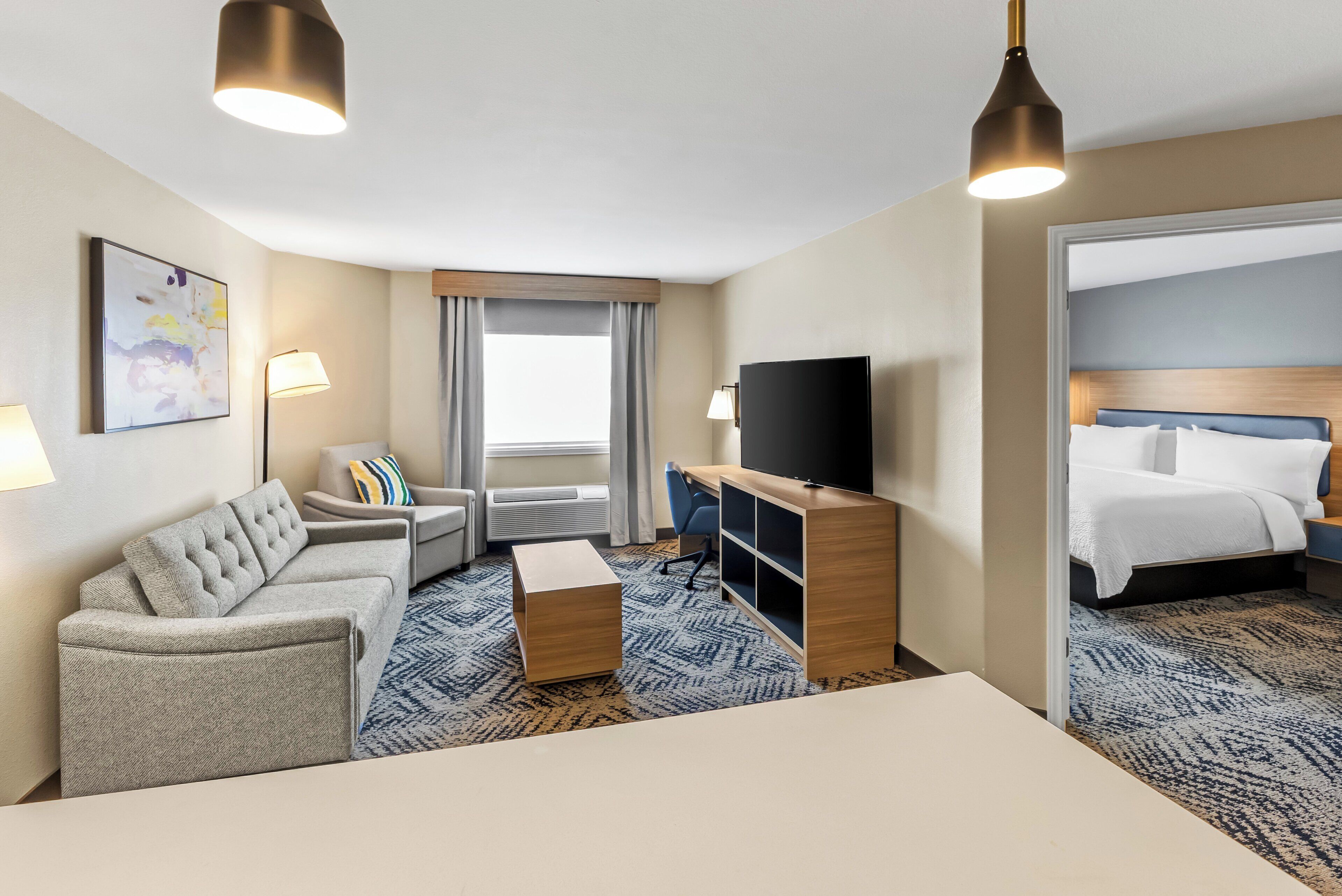 A hotel room with a sofa, a desk, a television, and a bed.