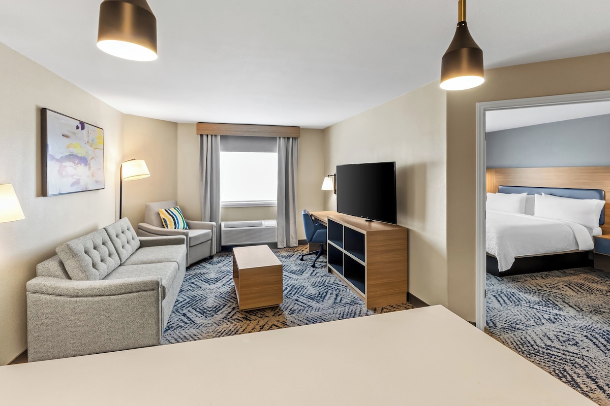 A hotel room with a sofa, a desk, a television, and a bed.