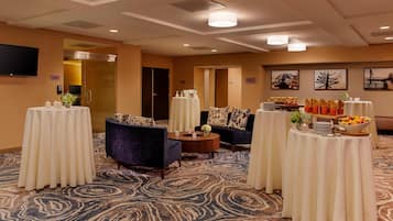 Un hall de hotel con mesas redondas, sofás y piso alfombrado.