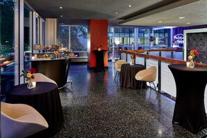 A modern bar area with a polished black floor, seating arrangements, and a bar counter with a wine display. - Courtyard by Marriott Portland City Center (Portland)