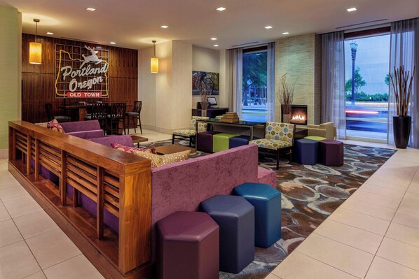 A lobby with a reception desk, seating area, and a fireplace. - Courtyard by Marriott Portland City Center (Portland)