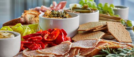 Una tabla de embutidos con diferentes carnes, quesos y galletas.