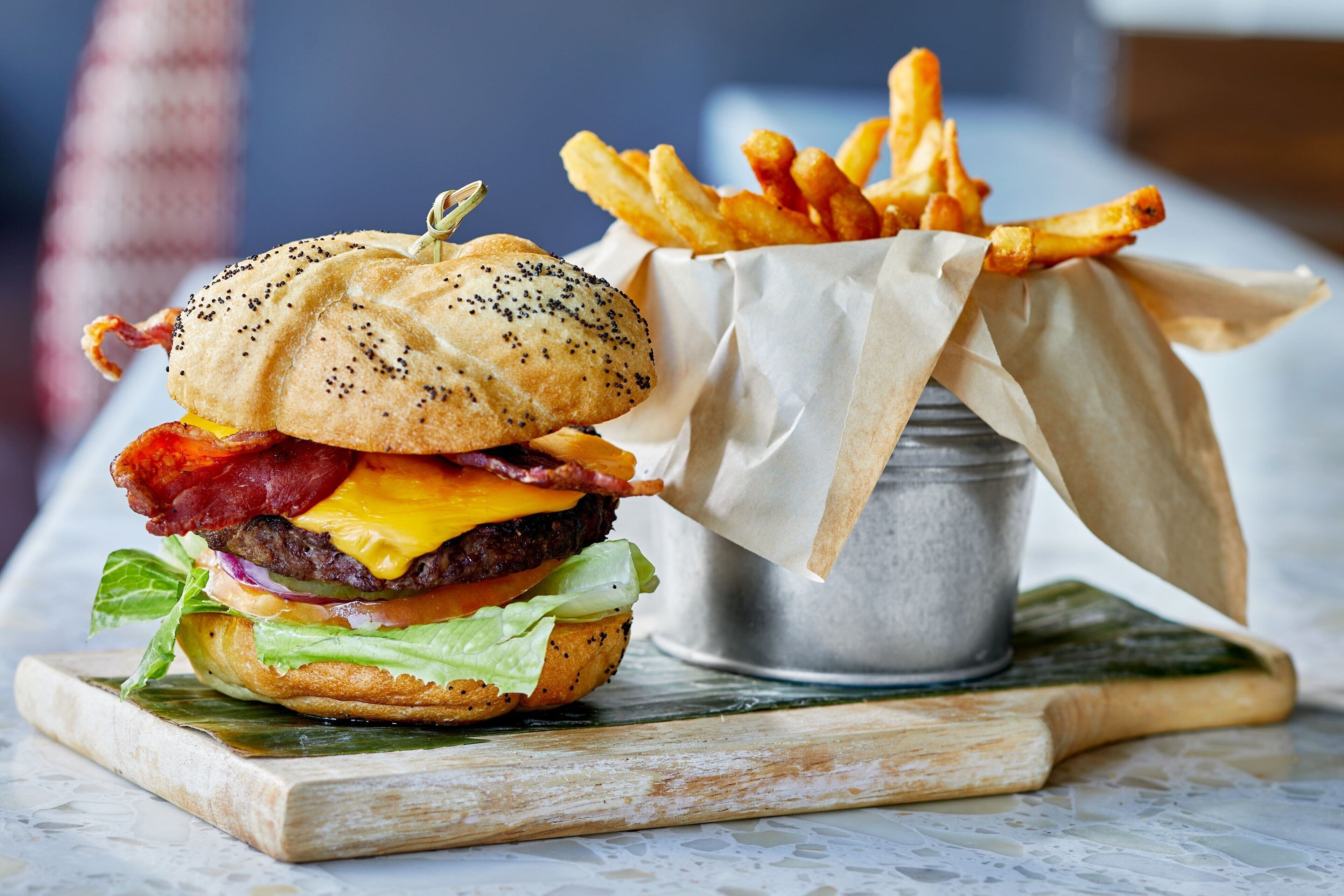 Un hamburger accompagné de frites, le tout servi sur une planche en bois.