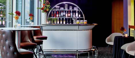 A bar area with a curved counter, multiple seating options including bar stools and chairs, and a variety of bottles and glasses on the shelves.