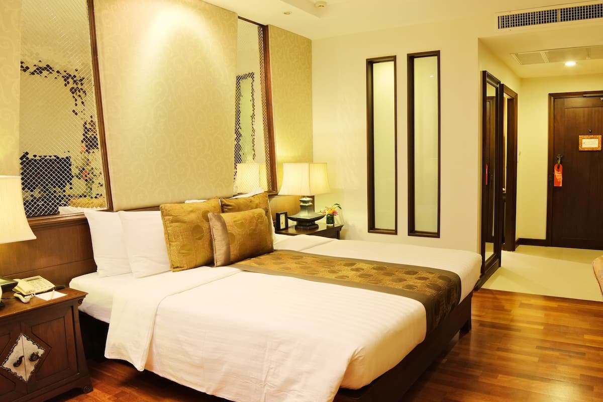 A hotel room with a large bed, a bedside table with a lamp, a mirror, and a door with a sign.