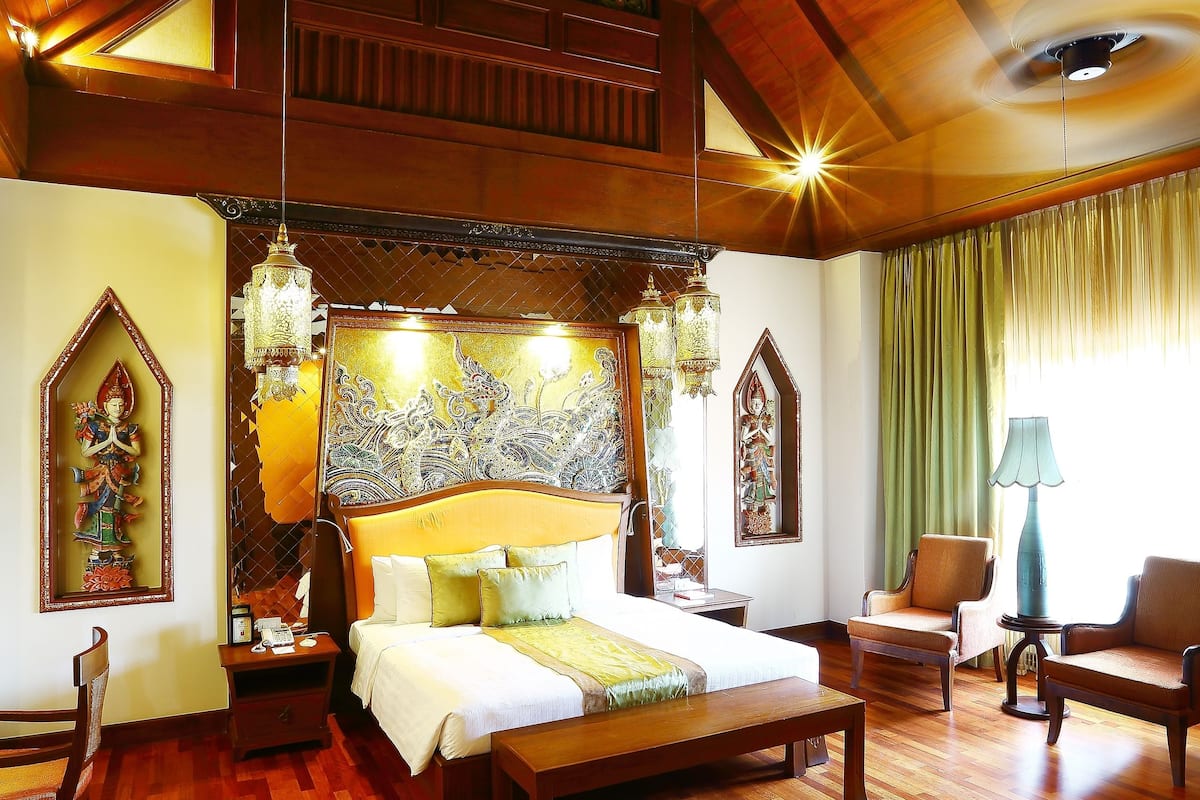 A spacious bedroom with a large bed, wooden ceiling beams, and traditional decor.