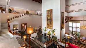 A spacious lobby with a high ceiling, a staircase, and a seating area with a red sofa. - Jaypee Residency Manor (Dehradun)