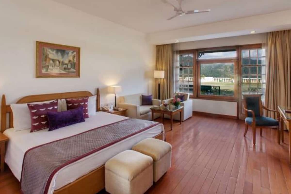 A hotel room with a large bed, a desk, a chair, and a view of the outdoors.
