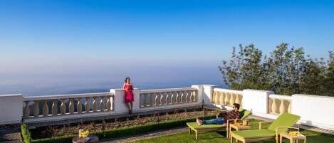 Une terrasse sur le toit offrant une vue dégagée sur l’horizon, une balustrade blanche et une petite table agrémentée de fleurs.
