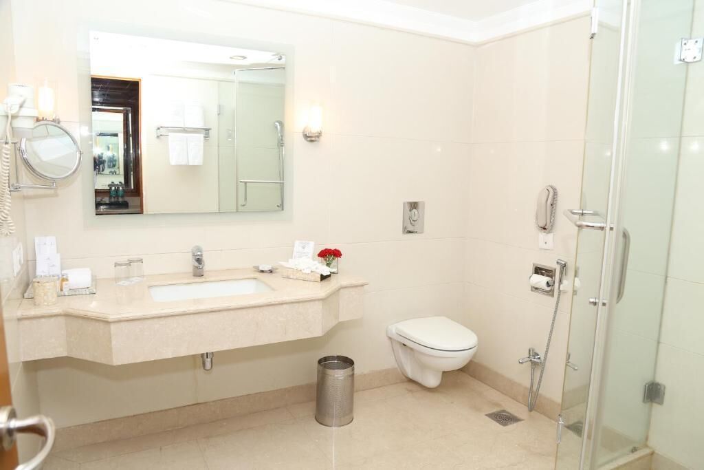 Un bagno moderno con un grande specchio, due lavandini, un water e una cabina doccia in vetro.