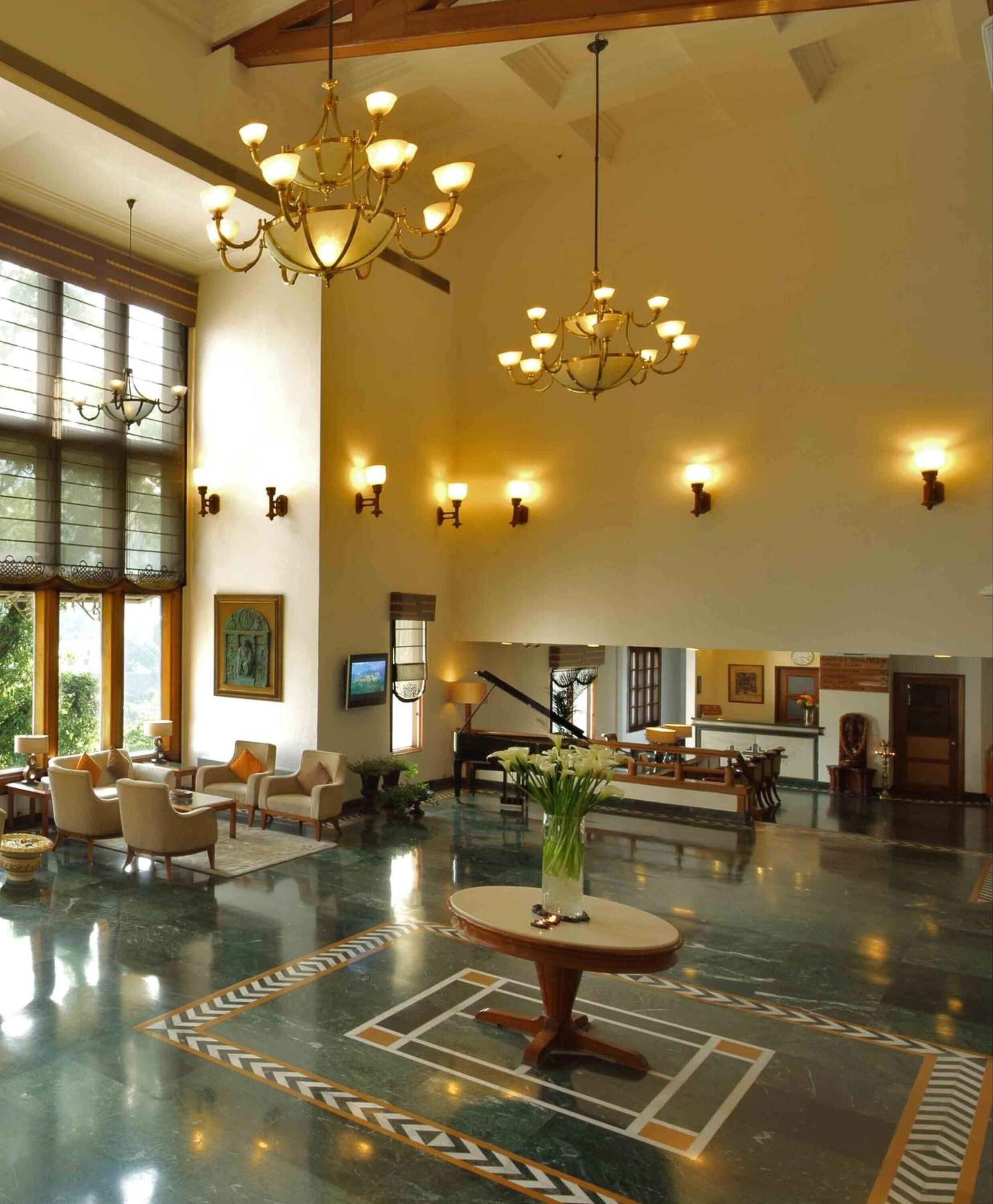 A spacious lobby with a grand chandelier, a piano, and a reception desk.