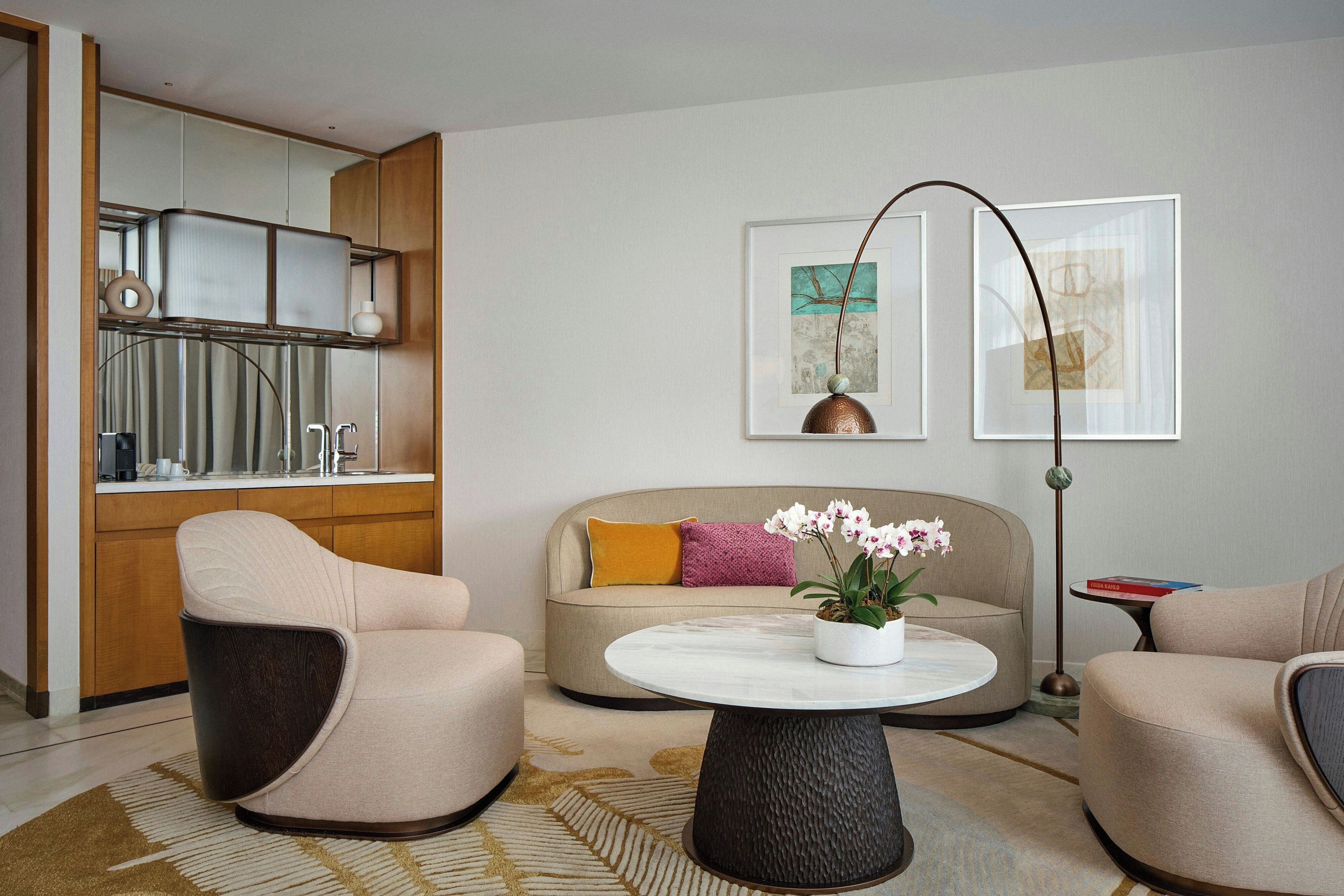 Ein modernes Wohnzimmer mit einer Couch, zwei Sesseln, einem Couchtisch und einer Stehlampe.