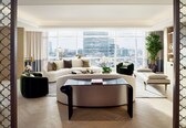 A modern living room with a large window, a sofa, a coffee table, and a green ottoman.