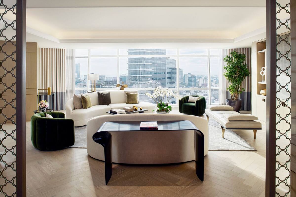 A modern living room with a large window, a sofa, a coffee table, and a green ottoman.