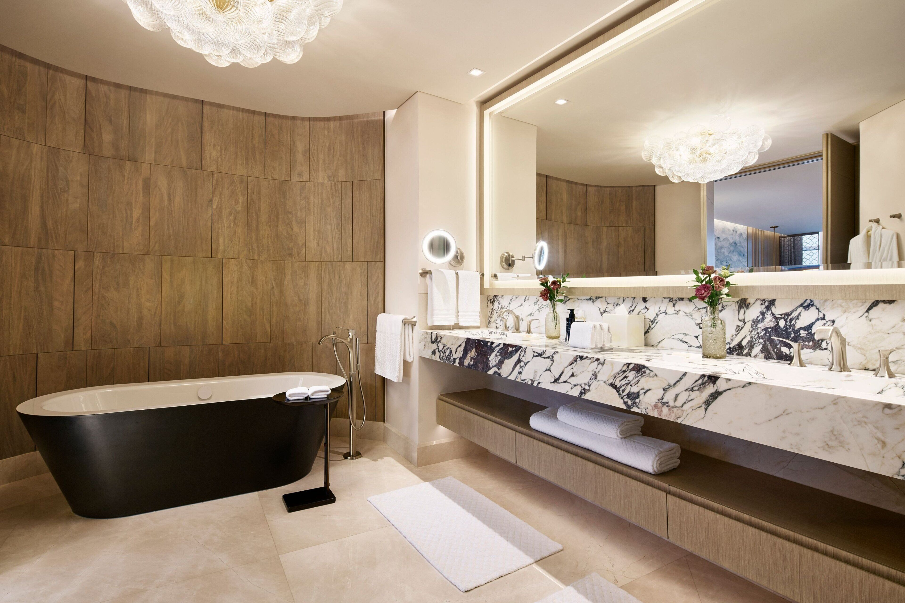 A modern bathroom with a freestanding bathtub, marble vanity, and a large mirror.