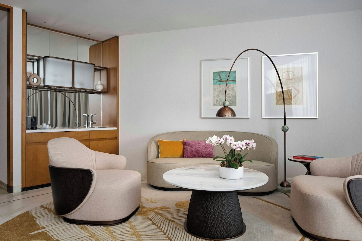 Una sala de estar moderna con un sofá, dos sillones, una mesita de centro y una lámpara de pie.