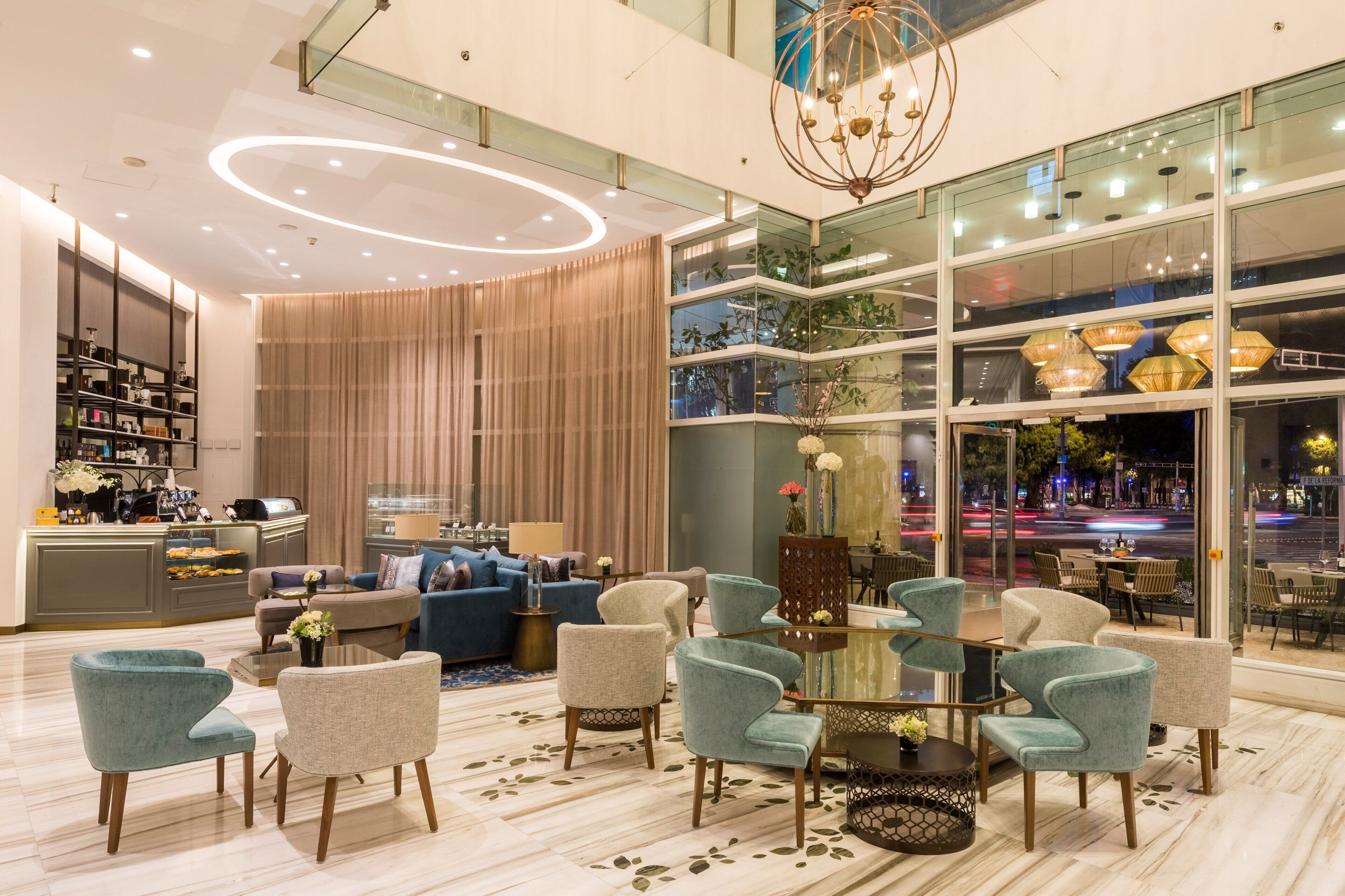 Eine moderne Hotellobby mit Sitzgelegenheiten, einer Bar und großen Fenstern mit Blick auf die Stadt.