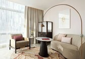 A modern living room with a sofa, armchair, round table, floor lamp, and a painting on the wall.