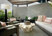 A modern outdoor seating area with a cushioned sofa, a wooden coffee table, and a lamp.