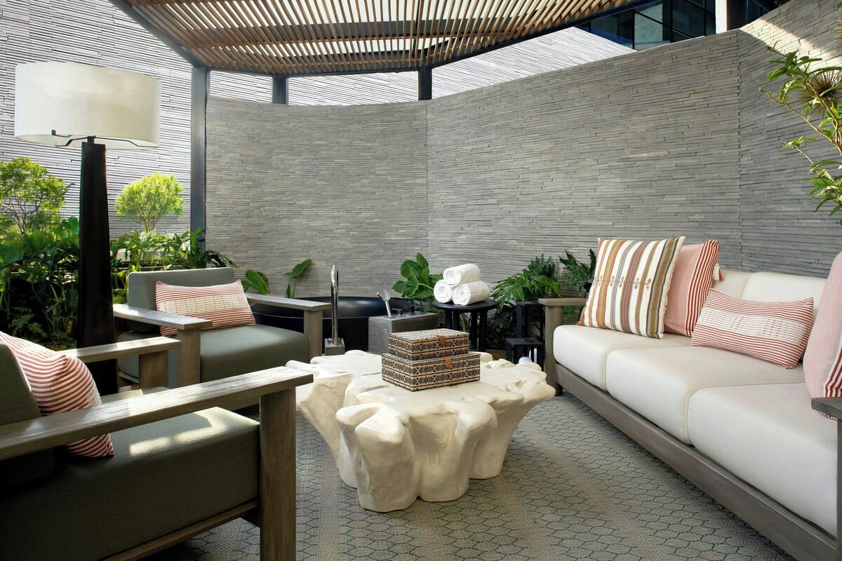 A modern outdoor seating area with a cushioned sofa, a wooden coffee table, and a lamp.