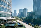 A modern hotel with a rooftop pool, lush greenery, and a view of the city skyline.