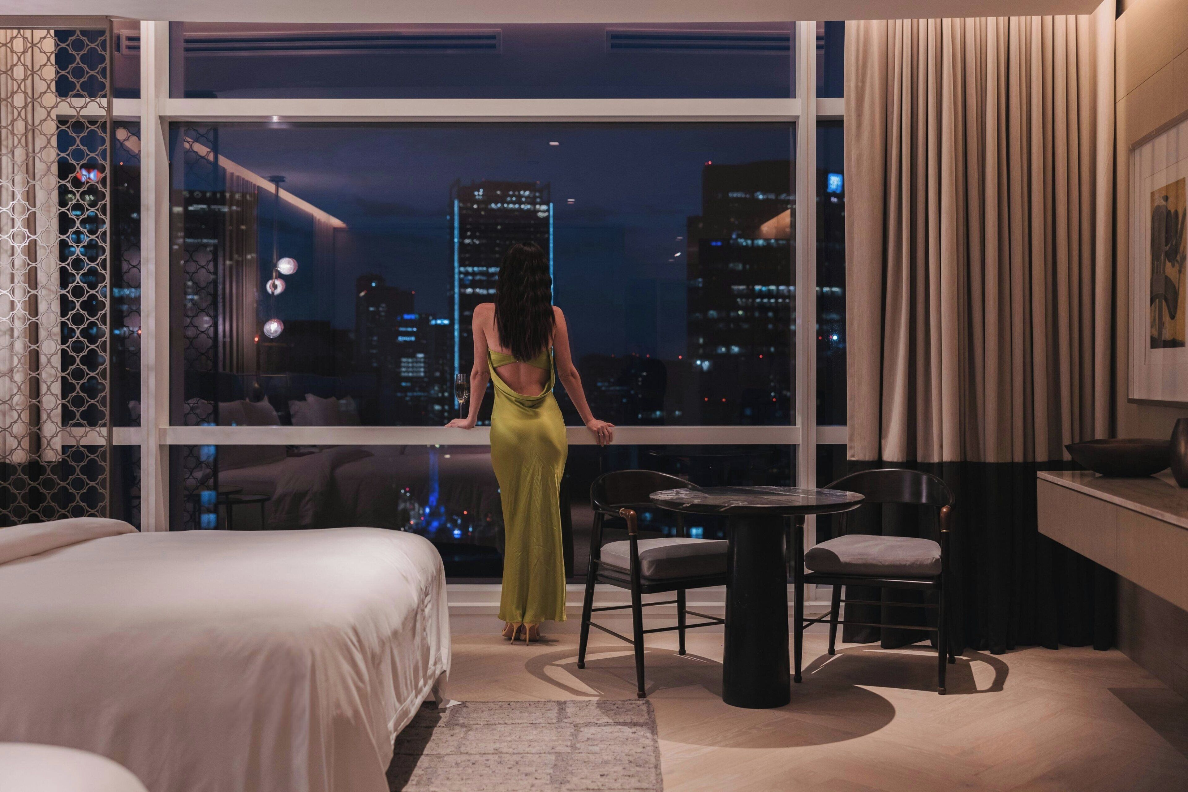 Habitación de hotel con un ventanal grande, una cama, una mesa de comedor y una silla.