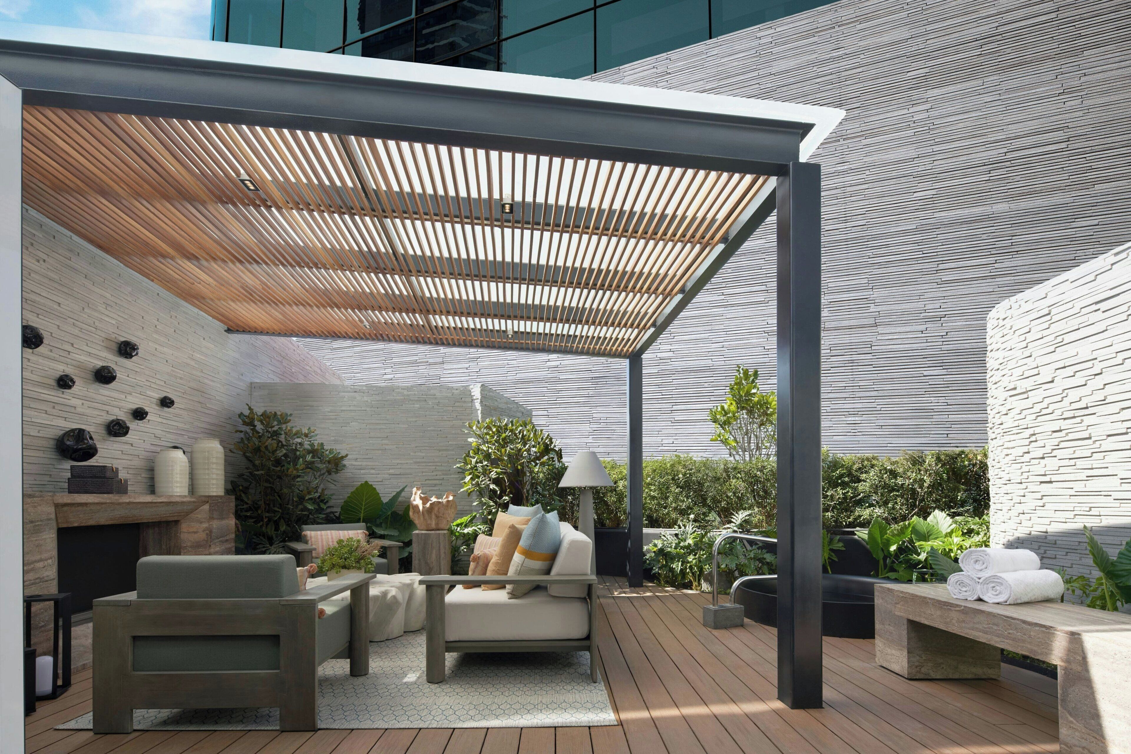 Une terrasse extérieure dotée d’une pergola en bois, d’un espace salon et d’un foyer.