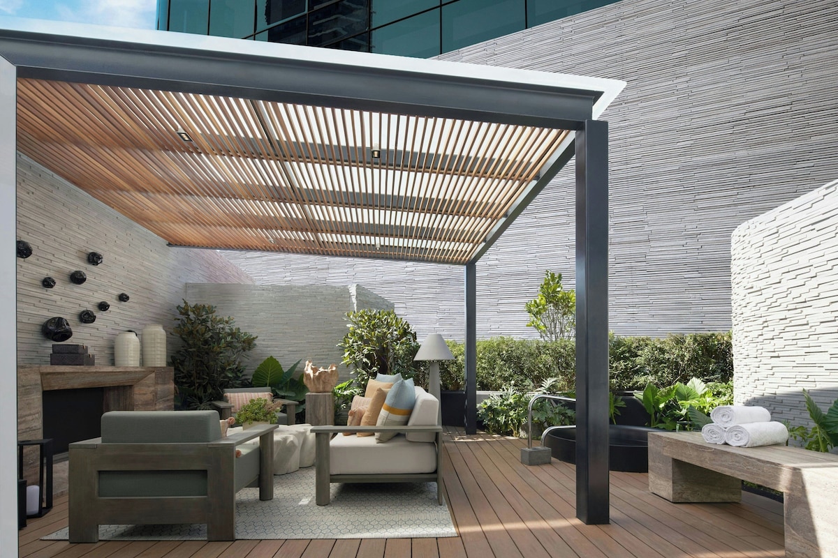 An outdoor patio with a wooden pergola, seating area, and a fire feature.