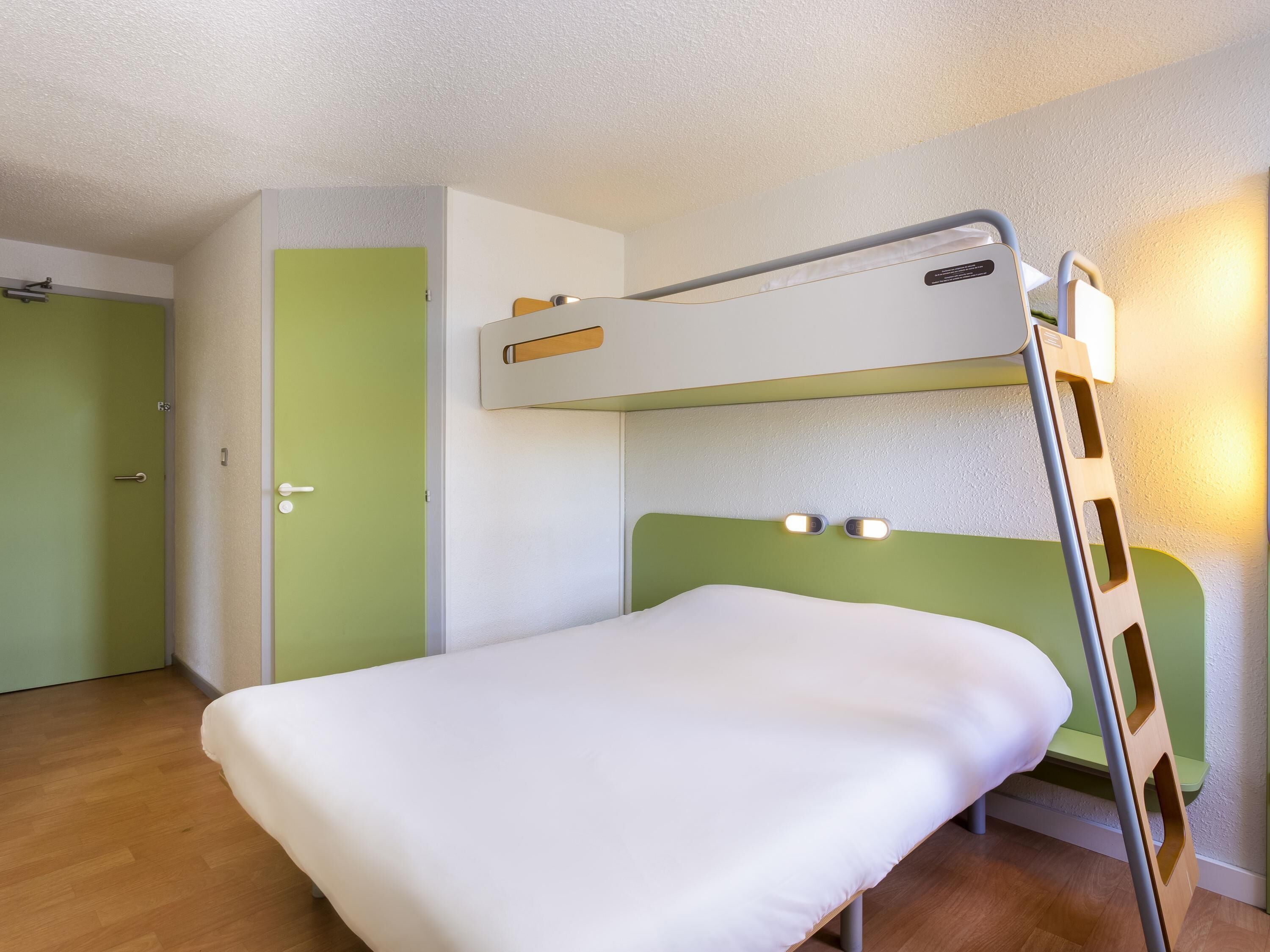 A bunk bed with a ladder, a white door, and a green wall.