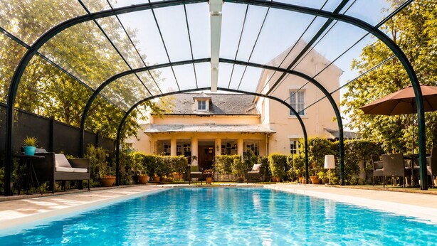 A swimming pool with a covered area, surrounded by potted plants and outdoor furniture. - Hôtel Villa Flornoy Pornichet Baie de la Baule (Pornichet)