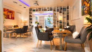 A modern interior with a dining area, seating, and a bookshelf. - Hôtel Villa Flornoy Pornichet Baie de la Baule (Pornichet)