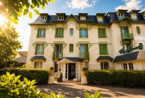 Un hôtel à la façade symétrique, aux volets verts, et sur lequel on peut lire l’inscription « Villa Flmoy ».